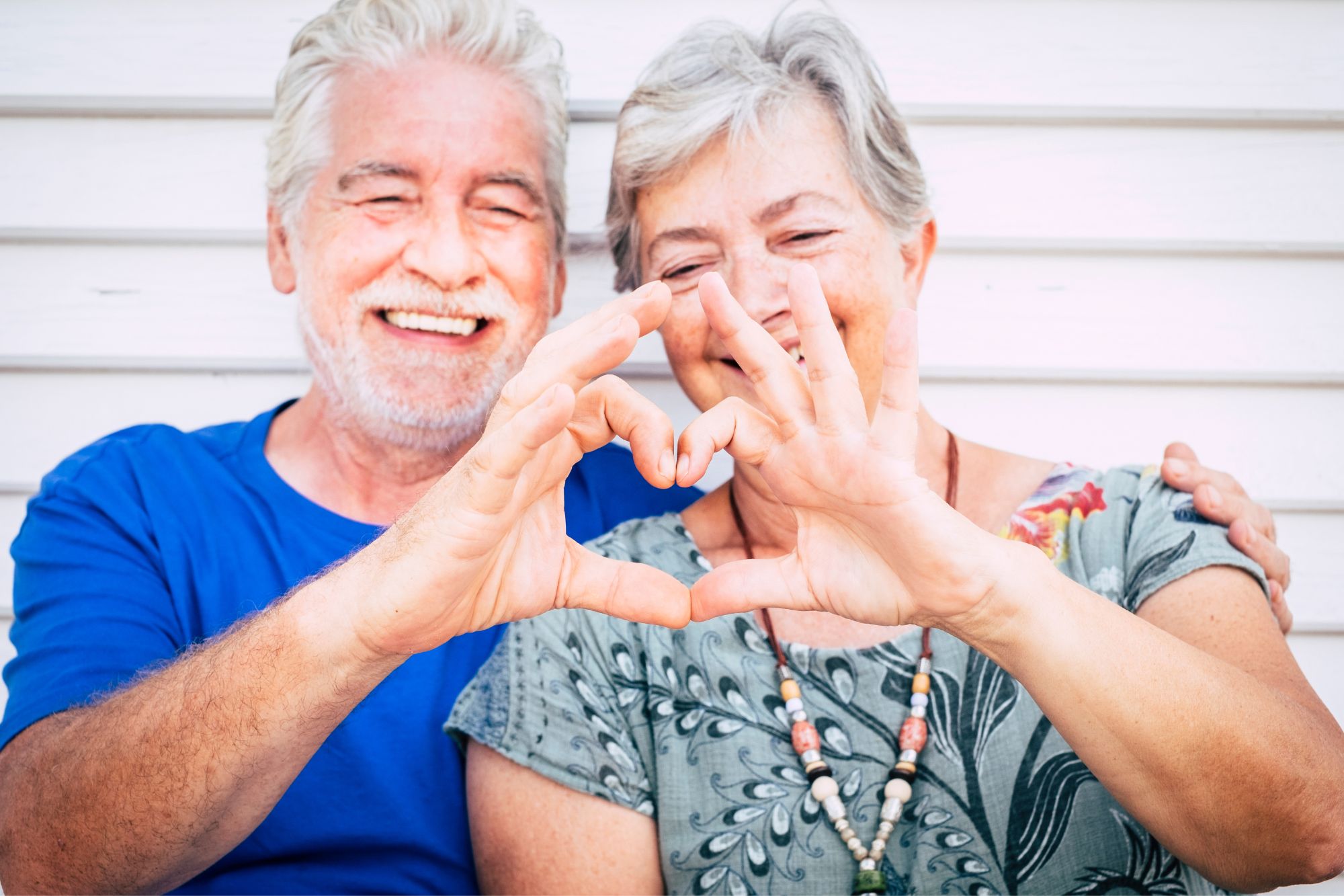 senior smiling couple making heart shape with hands