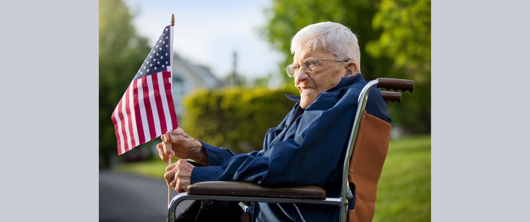 92 years old veteran sitting on his wheelchair holding an American flag